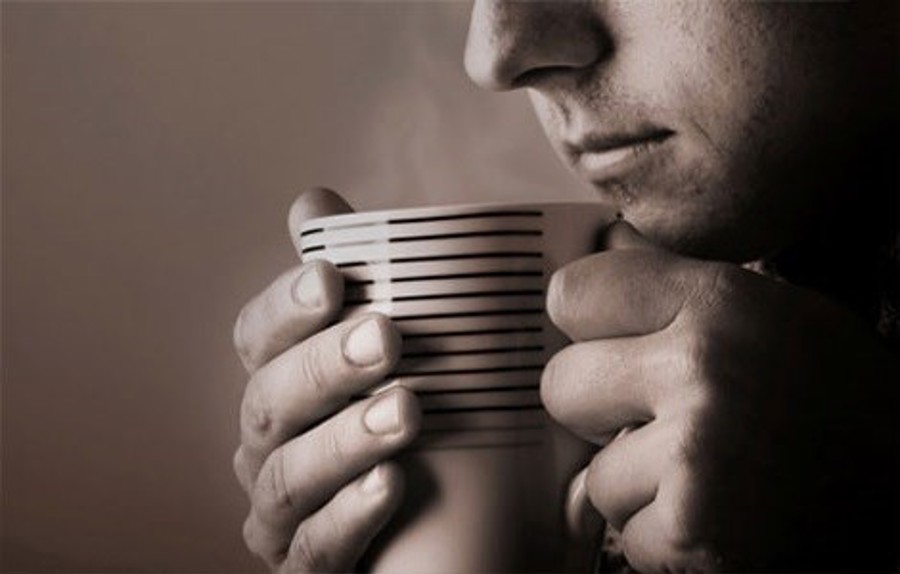 gråvitt foto av en man som dricker en kopp varmt kaffe i en randig kopp