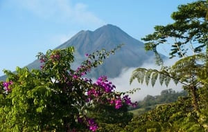 En vulkan omgiven av frodig vegetation och blommor, Arenal volcano Costa Rica